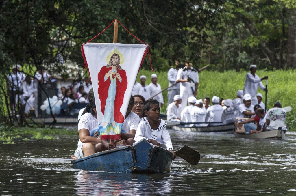 Pilgrims display a banner with an image of Christ as they travel in a boat in 2012 while accompanying the statue of Our Lady of Conception (not seen) along the Caraparu River in Santa Izabel do Para, Brazil. PHOTO: CNS/Paulo Santos, Reuters