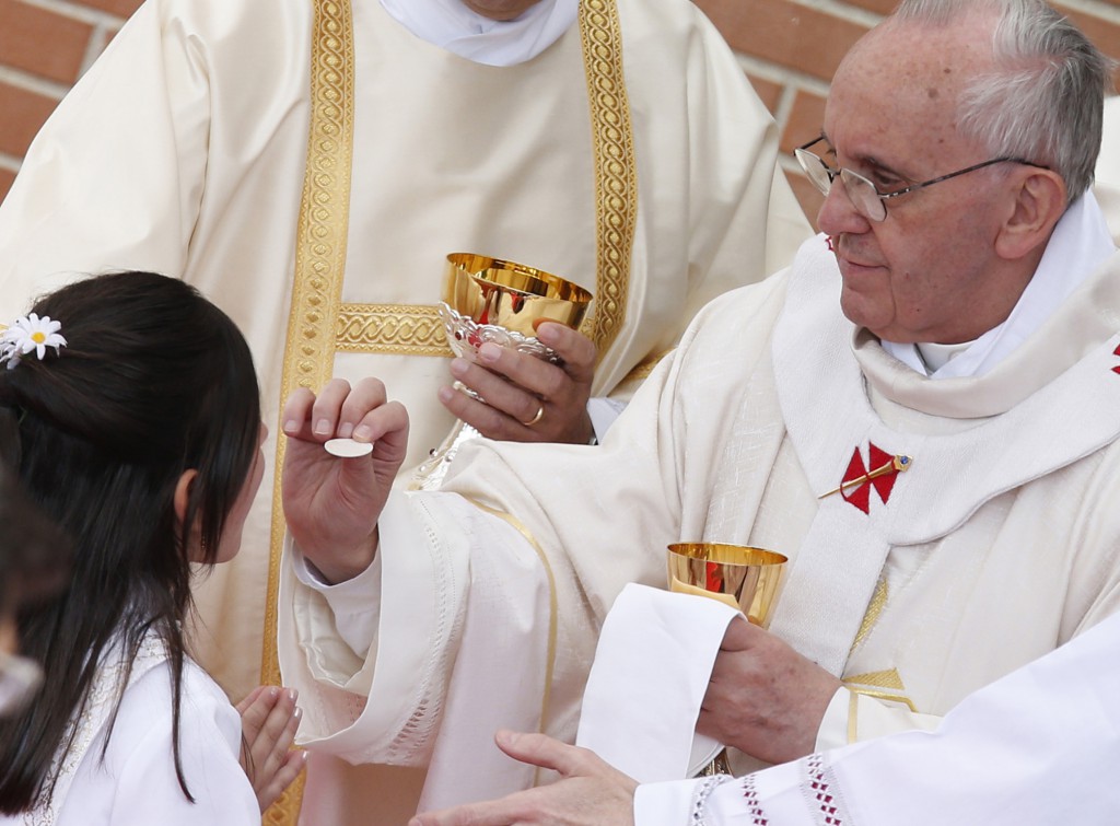 Pope Francis gives first Communion to a girl while celebrating Mass at Sts. Elizabeth and Zechariah Parish on the outskirts of Rome May 26. The pope gave first Communion to 16 children at the parish. PHOTO: CNS/Paul Haring