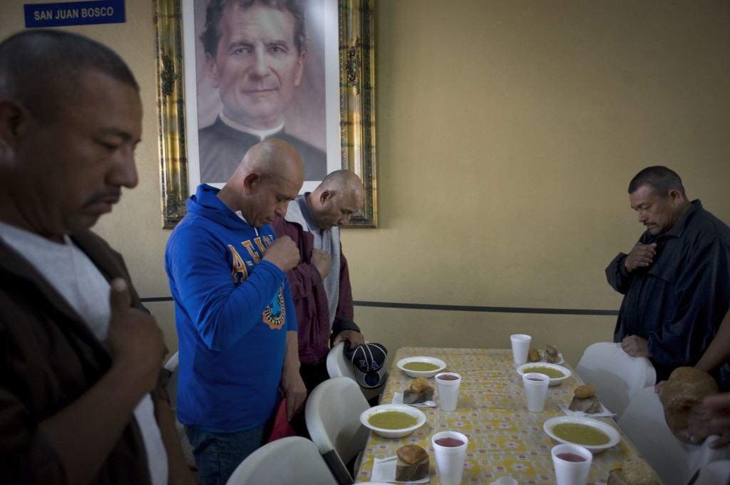 Men pray before sitting down to a meal at the Padre Chava breakfast center in Tijuana, Mexico, April 19. Each day the Salesian-run kitchen and shelter serves 1,200 meals, mostly to workers who have been deported from the U.S. PHOTO: CNS/David Maung