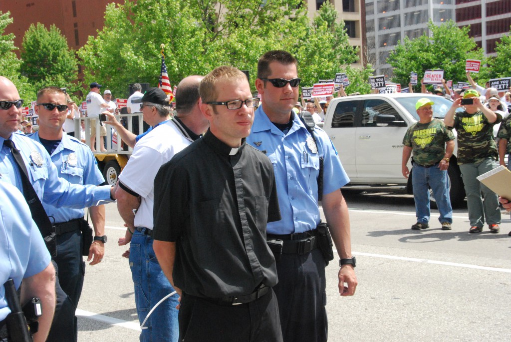 Police arrest Father Andrew Switzer, a West Virginia priest and the son of coal miners, during a May 21 union rally in St. Louis in this photo from the United Mine Workers of America. The rally was one of several organized by the union to protest a complex set of business maneuvers by Peabody Energy and Arch Coal involving a spinoff company. The corporate actions affect current and retired mine workers who may face salary loss and reduced pensions and health care coverage. PHOTO: CNS/David Kameras, courtesy of UMWA