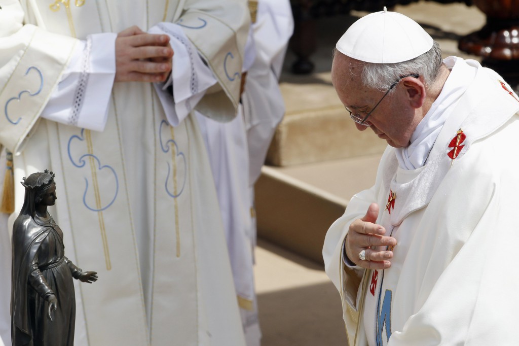 Pope Francis blesses himself in front of a statue of Mary as he celebrates a Mass Aug. 15 for the feast of the Assumption of Mary in the main square of Castel Gandolfo, a small town in the hills near Rome where previous popes have spent the summer months. PHOTO: CNS/Giampiero Sposito, Reuters