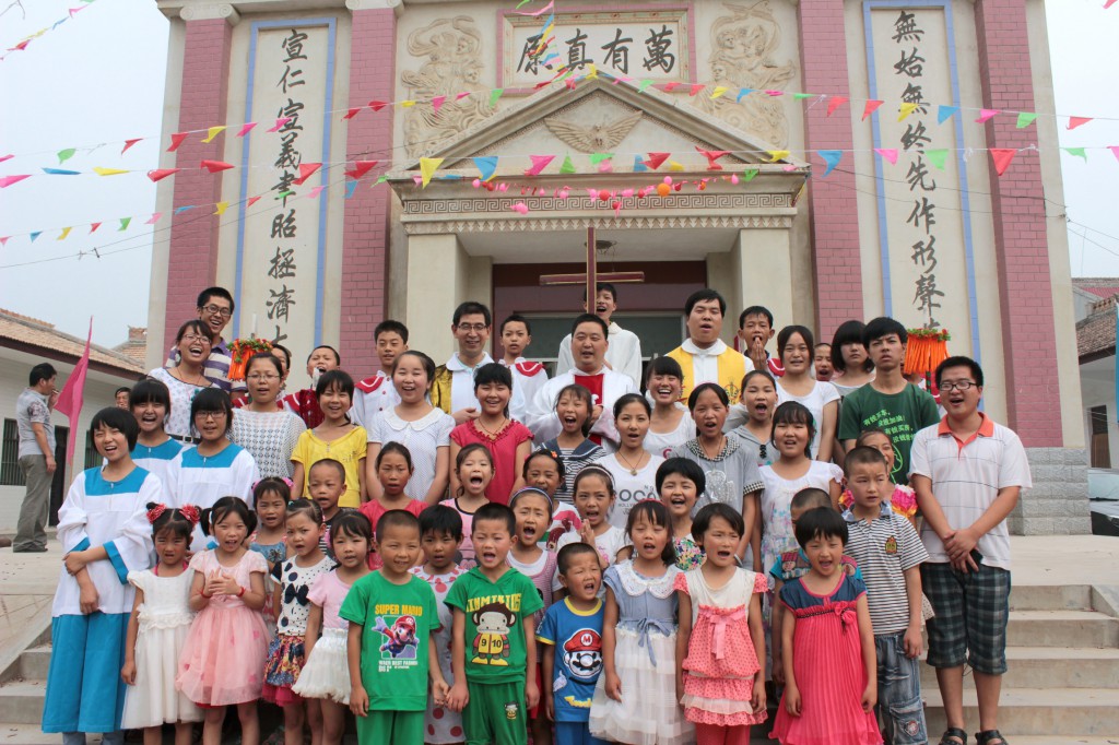 Children gather with parish priests for a photo on the steps of Sacred Heart of Jesus Church in the village of Fufengxian, in China's Shaanxi province, in late July. The Catholic parish was marking its 17th anniversary in a region known for its apple groves. PHOTO: CNS