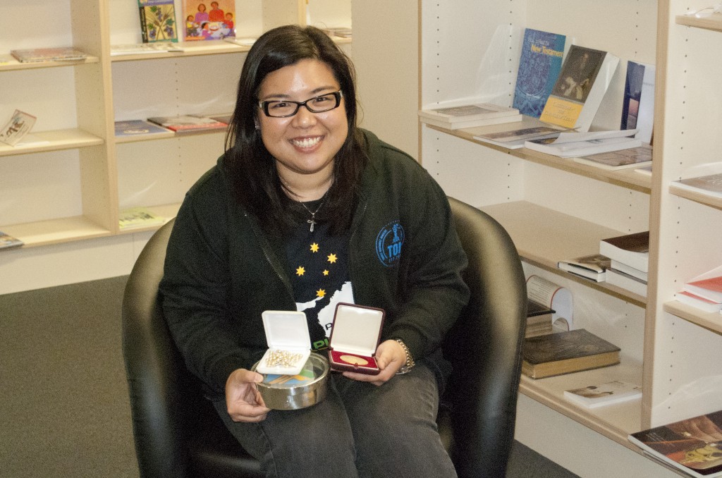 Josephine Yustira displays the Rosary, commemorative gold coin, and box of cookies she received as mementoes. PHOTO: Matthew Biddle