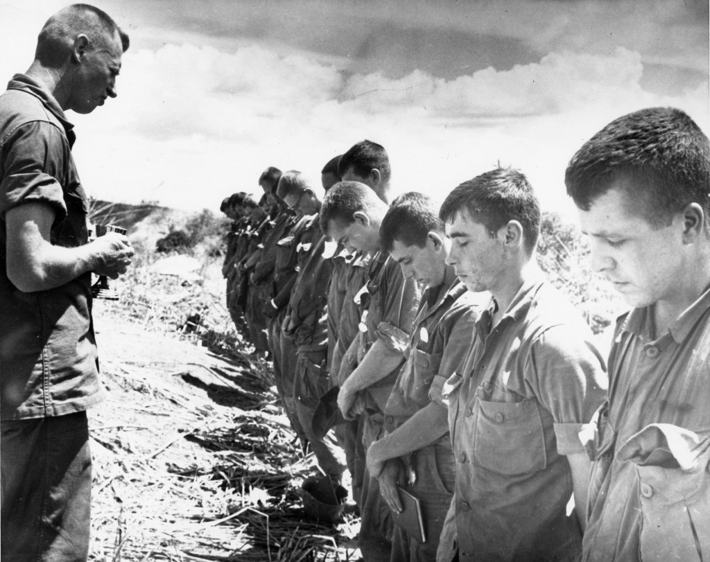 Maryknoll Father Vincent R. Capodanno, a Navy chaplain who was killed while serving with the Marines in Vietnam, is pictured praying with soldiers in an undated photo. As the priest's sainthood cause gathers momentum, he was remembered at a Sept. 4 memorial Mass in Washington as a man "completely dedicated to the spiritual care of his Marines." PHOTO: CNS/courtesy Maryknoll Fathers and Brothers