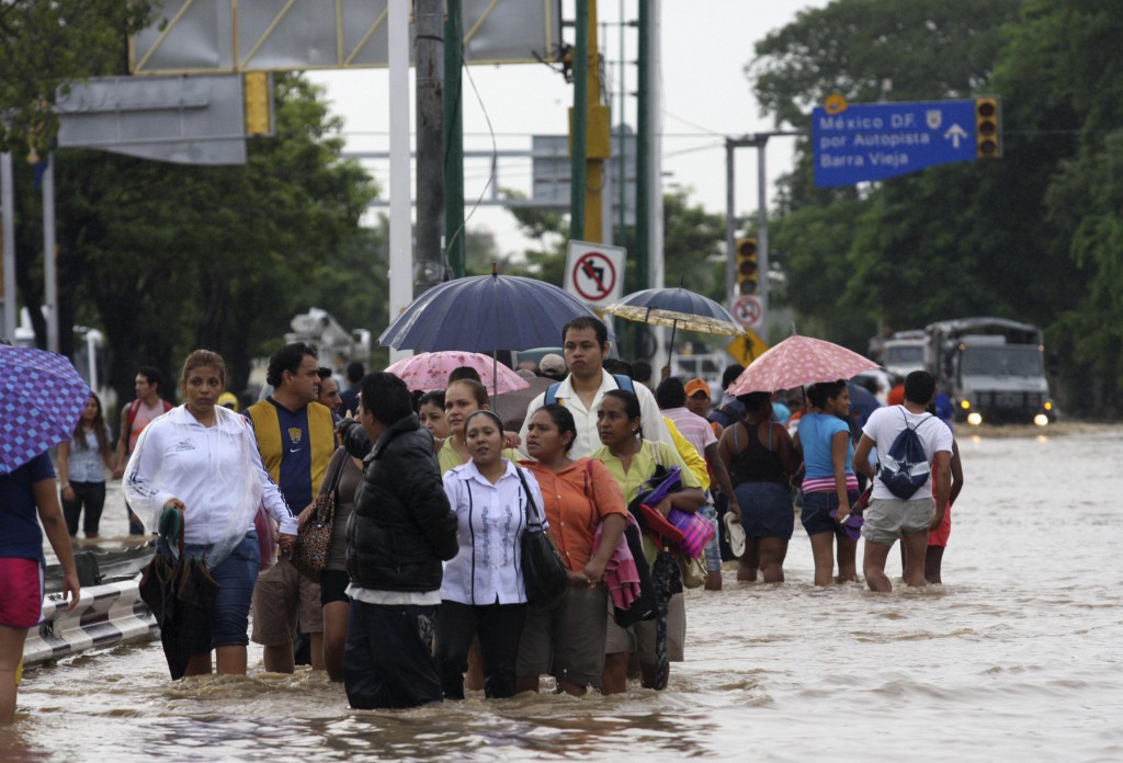 People walk through flooded streets in Acapulco, Mexico, Sept. 17. The Archdiocese of Acapulco has suspended church services and instructed priests to turn their parishes into support centers after torrential rains on one of the busiest weekends of the year left the city cut-off from other parts of Mexico. PHOTO: CNS/Jacobo Garcia, Reuters