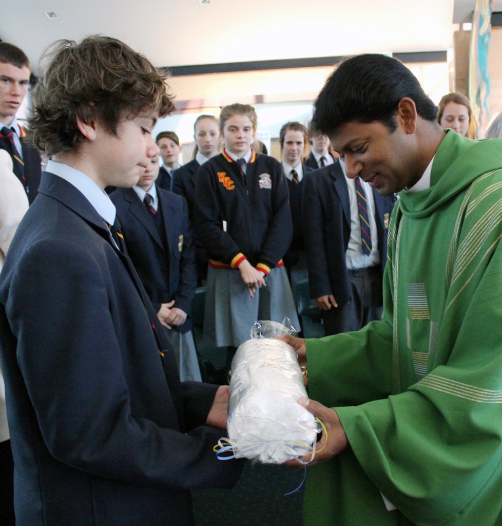 Fr George James receives the farewell gift of a Kolbe Catholic College towell, above, from students. Fr George has received a new parish posting after serving as assistant priest at Our Lady of Lourdes, Rockingham. PHOTO: Leanne Joyce