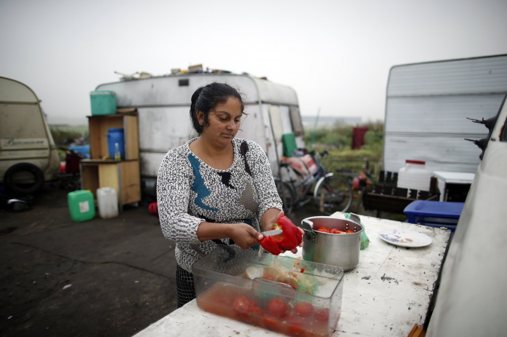 A Roma woman cooks vegetables at an encampment of families outside Paris Oct. 18. The president of the French bishops' conference criticized his country's attitudes to Roma and migrants and urged the Catholic Church to lead the way in upholding "fraternity, justice and solidarity" with the poorest. PHOTO: CNS/Benoit Tessier, Reuters