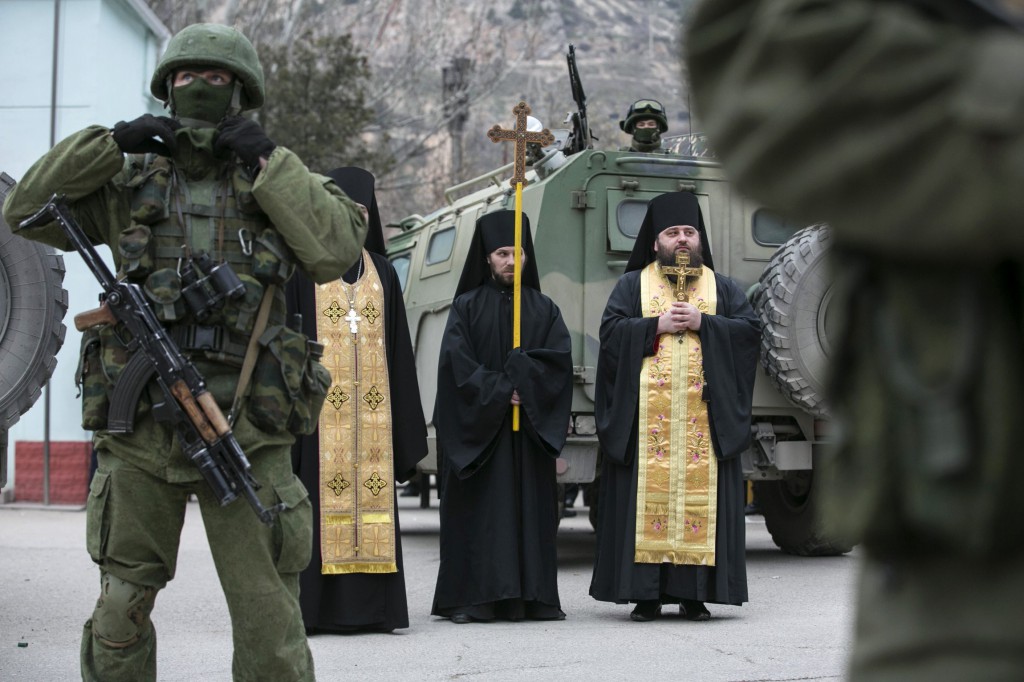 Orthodox clergymen pray next to armed servicemen near Russian army vehicles outside a Ukrainian border guard post in Ukraine's Crimean region March 1. Catholic leaders in Crimea say Ukraine has the right to determine its own future, and they urge prayers for peace. PHOTO: CNS/Baz Ratner, Reuters