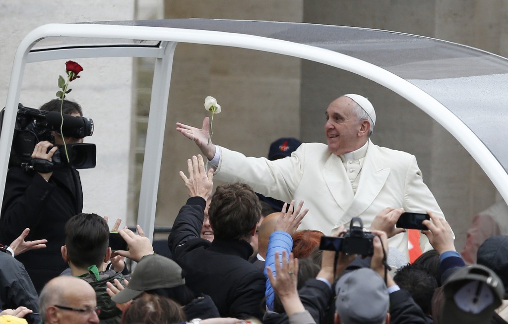 Pope Francis attempts to catch roses as he arrives to lead his general audience at March 26 in St. Peter's Square at the Vatican. CNS/Paul Haring