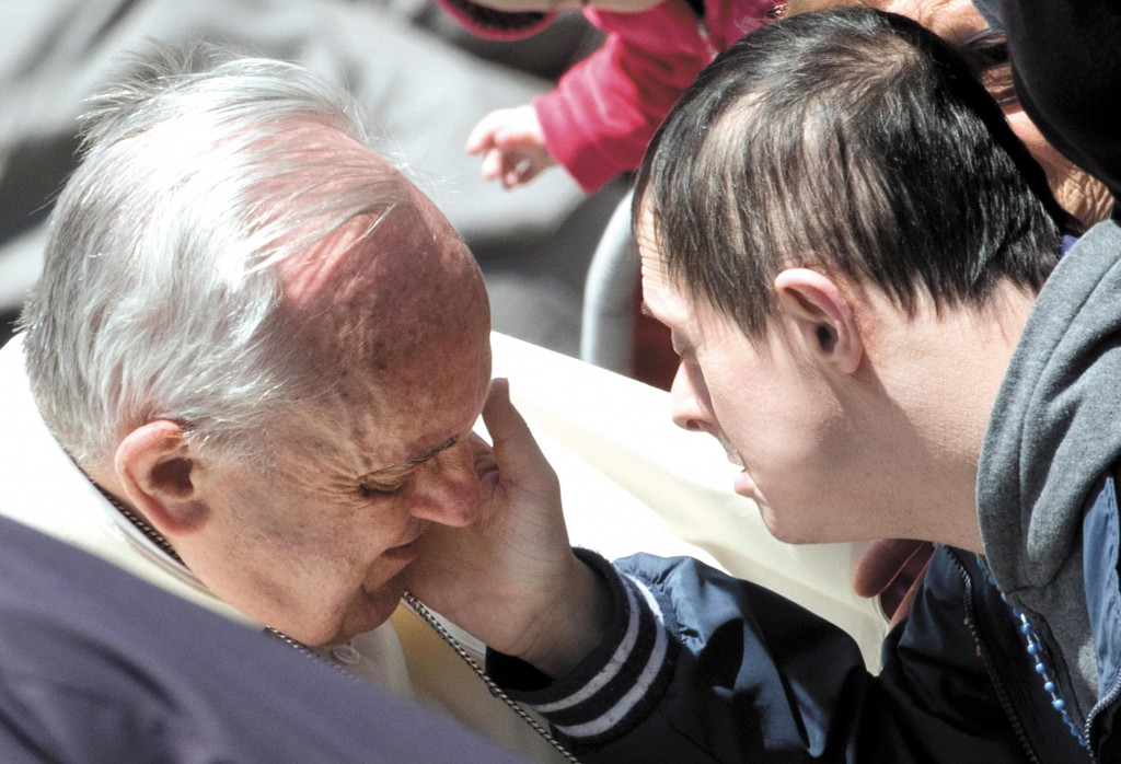 A young man touches the cheek of Pope Francis during the pontiff's weekly audience on May 14 in St. Peter's Square at the Vatican. PHOTO: CNS/Claudio Peri, EPA