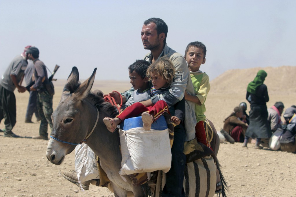 A man and three children flee violence from forces loyal to the Islamic State in Sinjar, Iraq, Aug. 10. Islamic State militants have killed at least 500 Yezidi ethnic minorities, an Iraqi human rights minister said. PHOTO: CNS/Rodi Said, Reuters