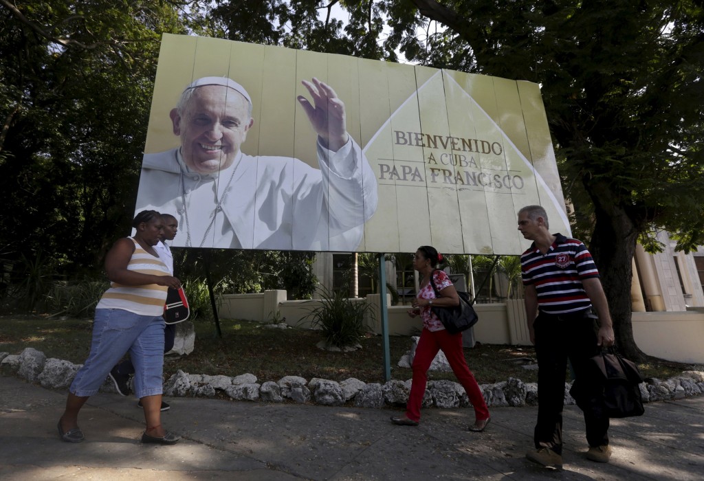 Cubans walk under a Pope Francis billboard in Havana, Sept. 14, 2015. Pope Francis' 10th foreign trip will be the longest of his pontificate and, with stops in Cuba, three U.S. cities and the United Nations, it also will be a "very complex trip," the papal spokesman said.  PHOTO: CNS/Enrique de la Osa, Reuters