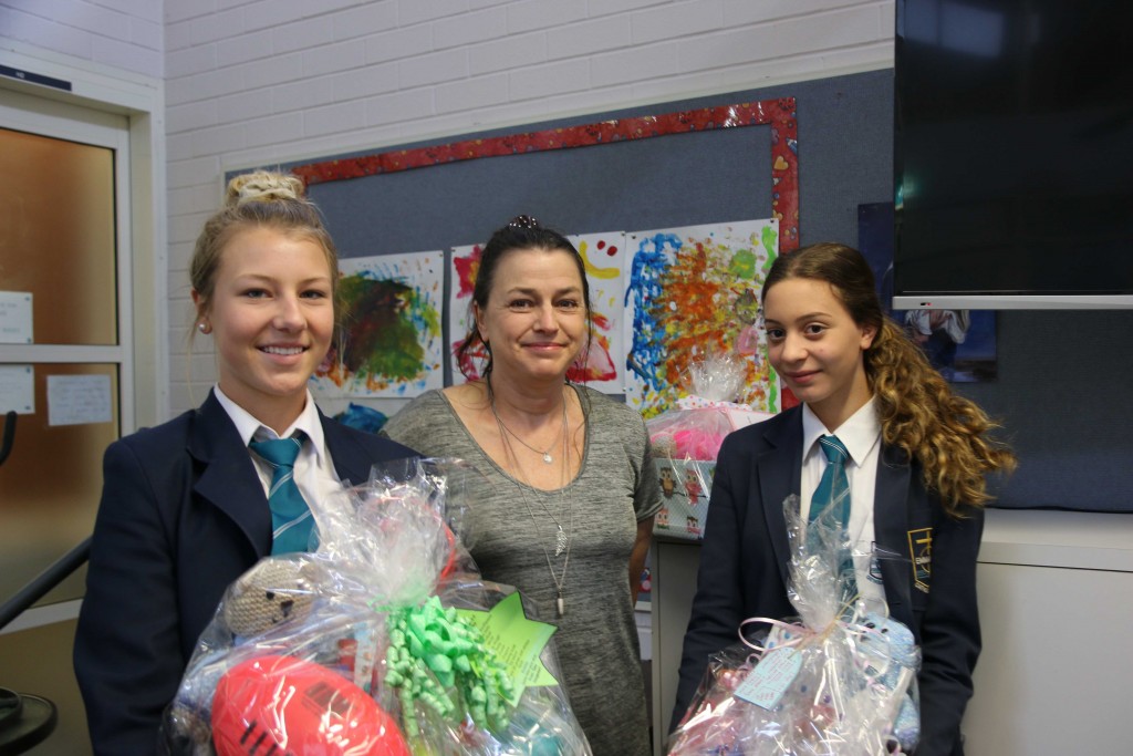 Emmanuel Catholic College Year 11 students, Talia Hoogewerf, left, and Sonia Caiulo, right, present Care Packages to Lisa Martin from the Wanslea Foster Care program. PHOTO: Supplied