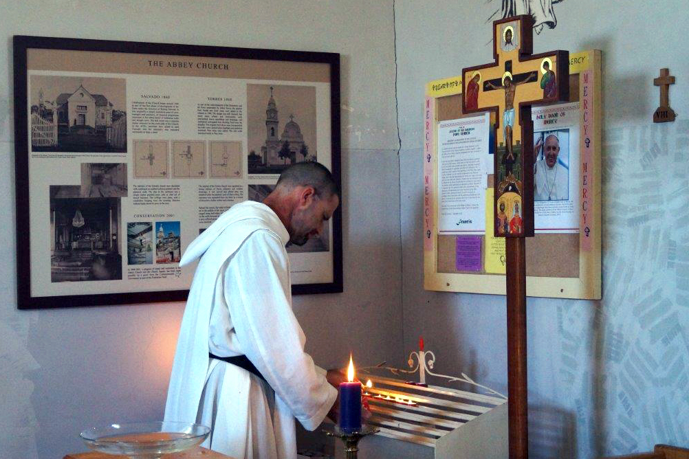 Dom Robert Nixon lights a candle inside the church at New Norcia, which dates from the 1840s. Photo: Supplied.