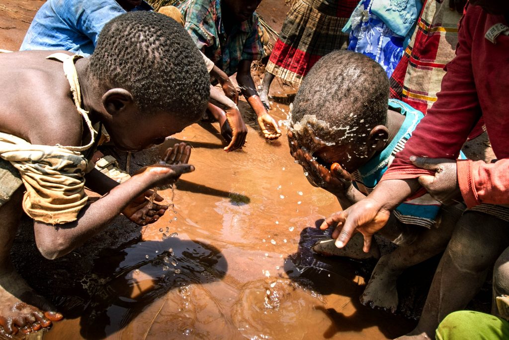 Refugee children wash their faces in a puddle in the refugee camp at Mwanza, Malawi on 8 February. Malaria and cold nights add to the suffering of the increasing number of Mozambicans arriving at a makeshift camp in Malawi to escape violence at home, said a Church worker in Malawi. Photo: CNS/Erico Waga, EPA