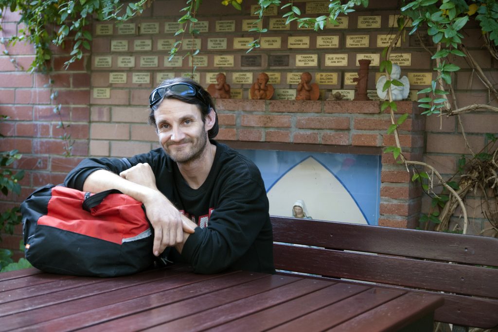 Benn Roberts, pictured in front of The Shopfront’s Memorial Wall, has received public transport and clothing vouchers to help him get back on his feet. Photo: Rachel Curry