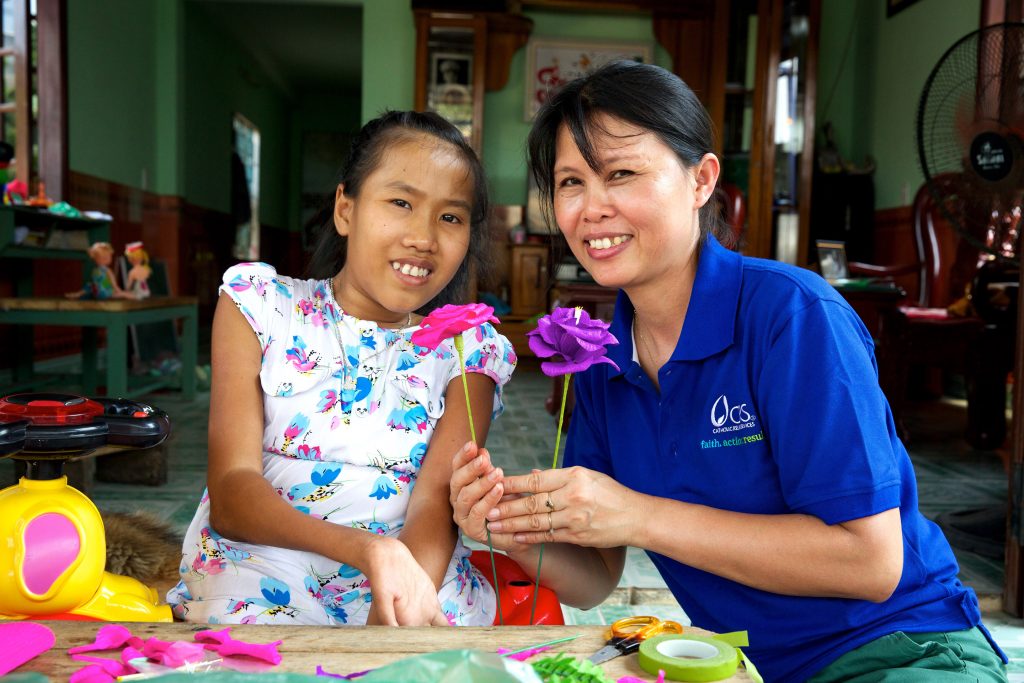 Nguyet at home showing CRS Program Manager Thao Le how to make paper flowers. Richard Wainwright/Caritas Australia