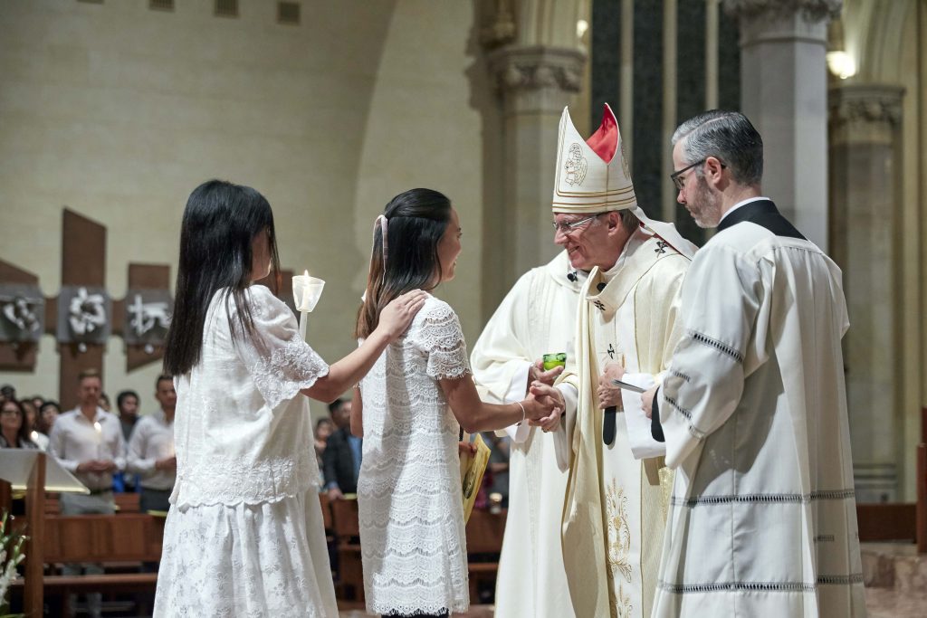 Archbishop Costelloe congratulates a baptismal candidate at the Easter Vigil Mass held at St Marys Cathedral. Photo: Ron Tan.