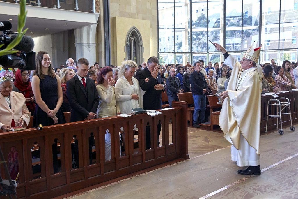 Parishioners of St Mary’s Cathedral receive a blessing at the beginning of the Easter Vigil Mass on 20 April. Photo: Ron Tan.