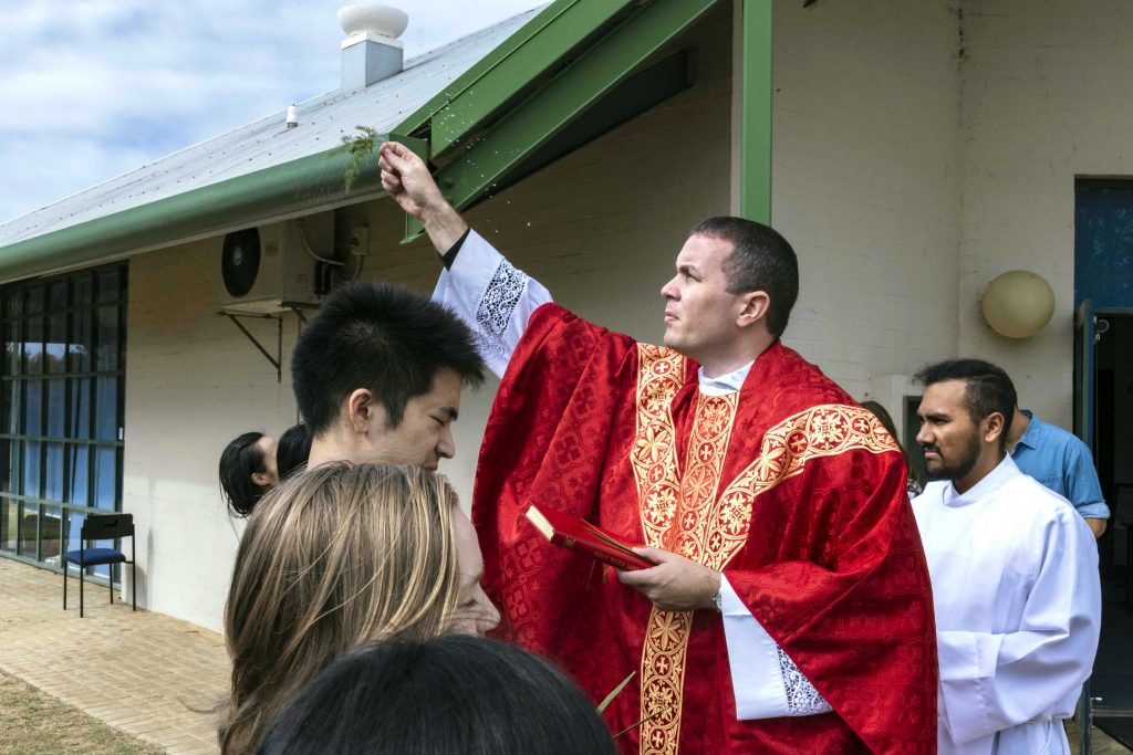 North Beach Parish Assistant Priest and CYM Chaplain Fr Mark Baumgarten blesses the palms before morning Mass on Sunday 14 April. Photo: Matthew Lau.