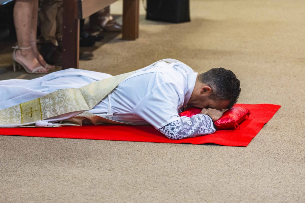 Fr Christopher John Maria De Sousa CRS prostrates himself before the Altar at St Jeromes, Spearwood. Photo: Matt Lau.