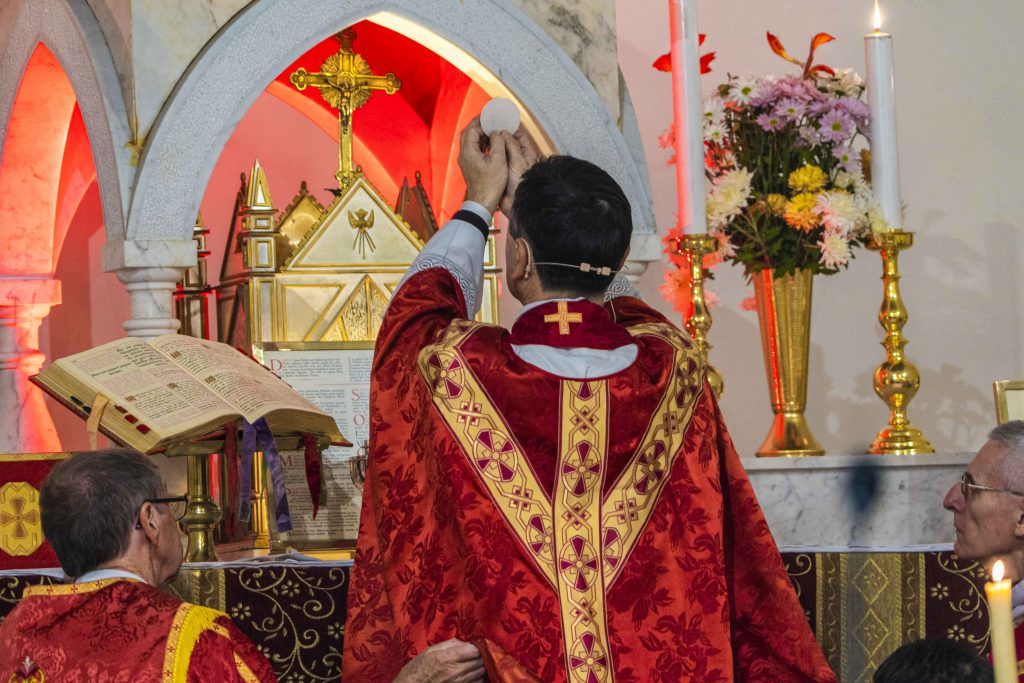 Fr Rowe elevates the Eucharist during the Mass to celebrate his 25 years of the priesthood. Photo: Josh Low.