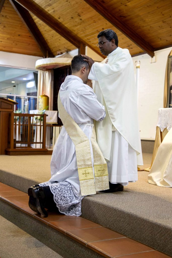 Fr Johnson Joseph CRS lays his hands in prayer on now Fr Chris’ head during the Rite of Ordination. Photo: Jamie O’Brien.