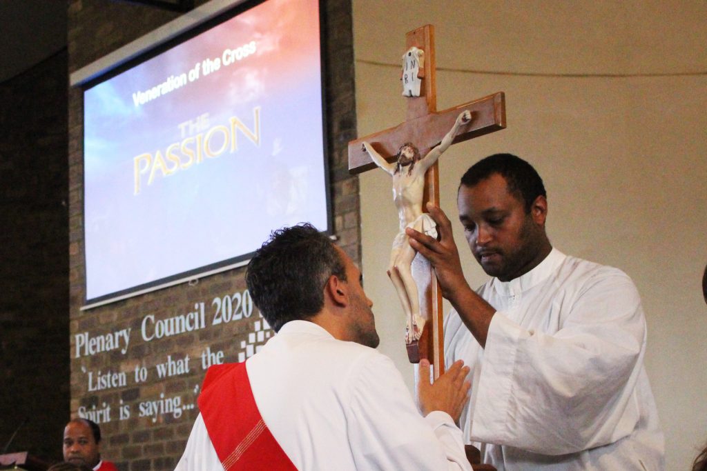 Soon-to-be-priest Deacon Chris de Sousa CRS kisses the feet of Jesus during the veneration of the Cross at OLOL Church on Good Friday, 19 April. Photo: Supplied.