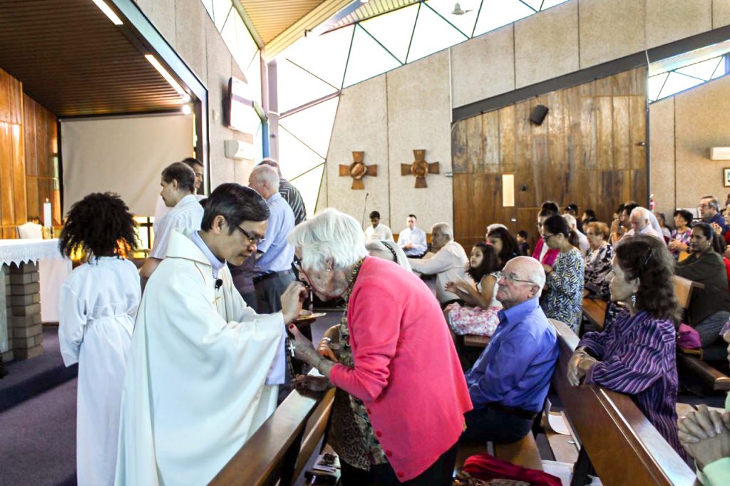 Sheelah Rudman receives Holy Communion from Fr Michael Quynh Do at Notre Dame Church in Cloverdale. Photo: Sunil Rodrigues.