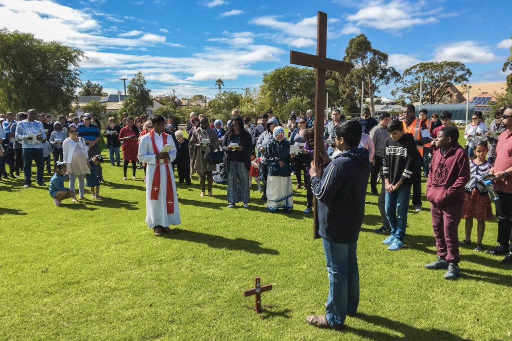 St Mary’s Church Assistant Parish Priest Fr Renald Anthony is seen standing before the cross, carried by a young parishioner on Good Friday, 19 April. Photo: Robert Hicks.